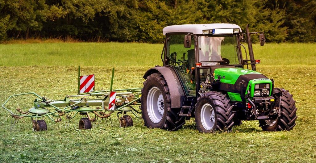 Trattore con attrezzatura per rivoltare il fieno in un campo